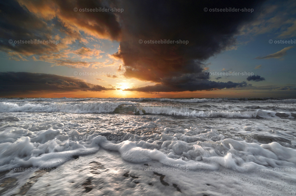 Vorhang auf für ein Schauspiel am Abend | Neben einer großen dunklen Wolke geht die Sonne über der Ostsee unter, während Wellen das Schauspiel akustisch begleiten.