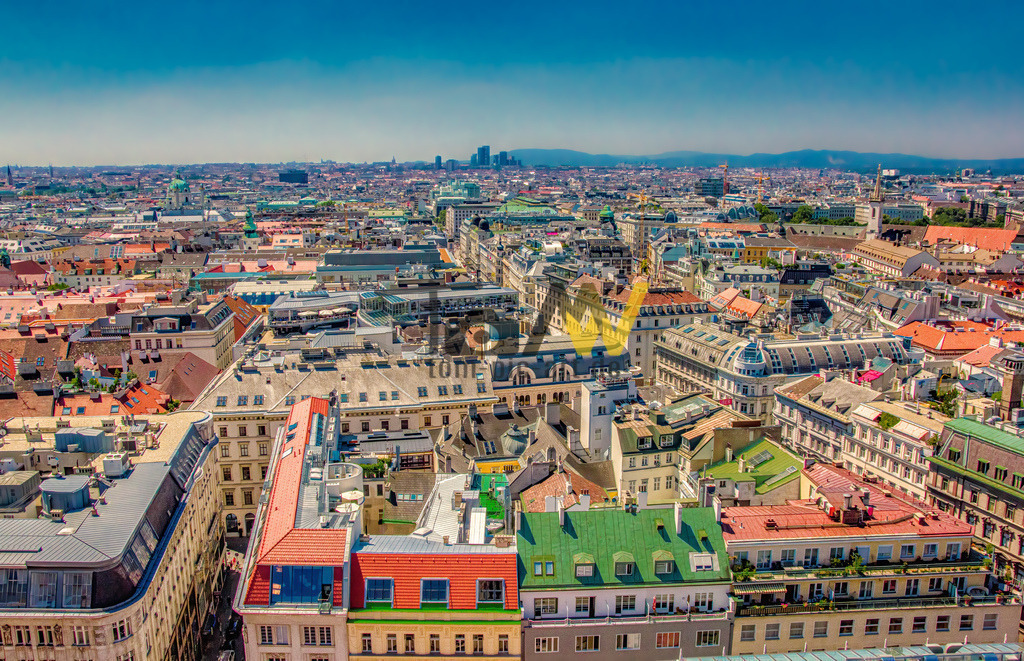 Panoramablick über die Stadt von Wien von oben-----II | Die Aufnahme zeigt eine Panoramaaussicht über die Dächer der Wiener Innenstadt, aufgenommen vom Südturm des Stephansdoms.Der Stephansdom, von dessen Turm die Aufnahme stammt, ist das Wahrzeichen Wiens und ein römisches-katholisches Gotteshaus. Das Dach des Doms ist mit bunten Ziegeln gedeckt, die unter anderem den k.u.k. Doppeladler sowie die Wappen von Wien und Österreich zeigen.  - Realisiert mit Pictrs.com