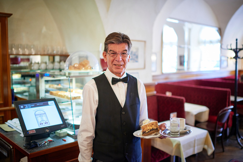 Cafe Frauenhuber | Wien, Austria - August 23, 2017: Cafe Frauenhuber, Herr Hannes serviert eine Haustorte mit Schlagsahne und Melange. - Realisiert mit Pictrs.com