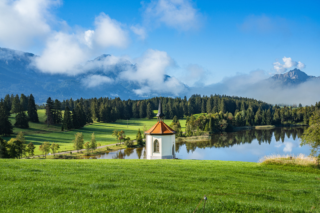 Allgäu Wandbild - Kapelle am Hegratsrieder See | Für dieses Bild von der bekannten Kapelle am Hegratsrieder See musste ich ein wenig warten, bis sich der Nebel verzogen hatte. Aber als das erste Blau des Himmels zu sehen war, wusste ich, dass es sich gelohnt hatte :-)