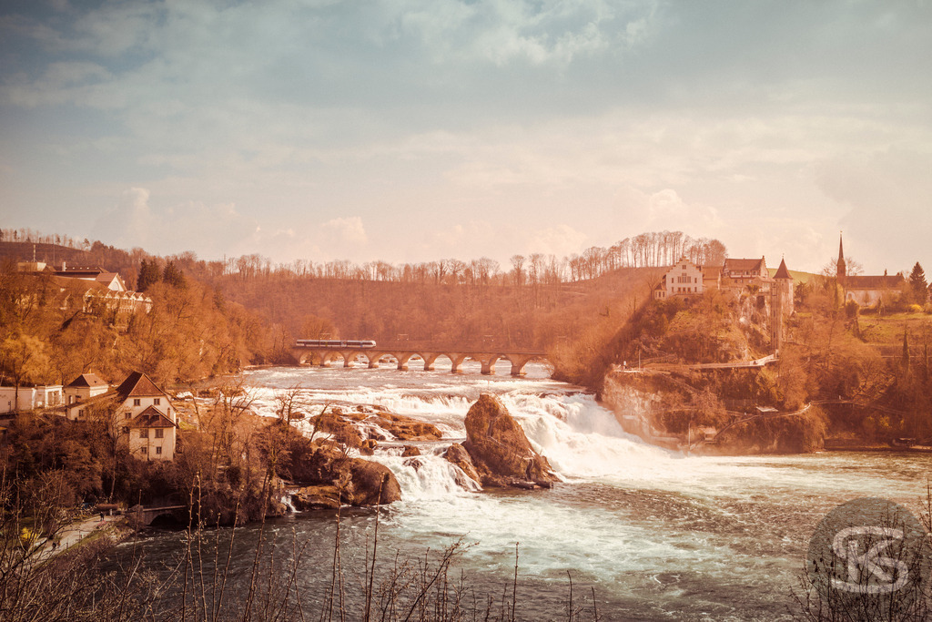 Der Rheinfall bei Schaffhausen und Schloss Laufen | Eine historische Ansicht des Rheinfalls, Europas größtem Wasserfall, in der Schweiz. Das Bild zeigt das tosende Wasser des Rheins, die umliegende bewaldete Landschaft und das markante Schloss Laufen auf der rechten Seite. Ein eindrucksvolles Zeugnis der Naturkraft und der frühen Fotografie. - Realisiert mit Pictrs.com