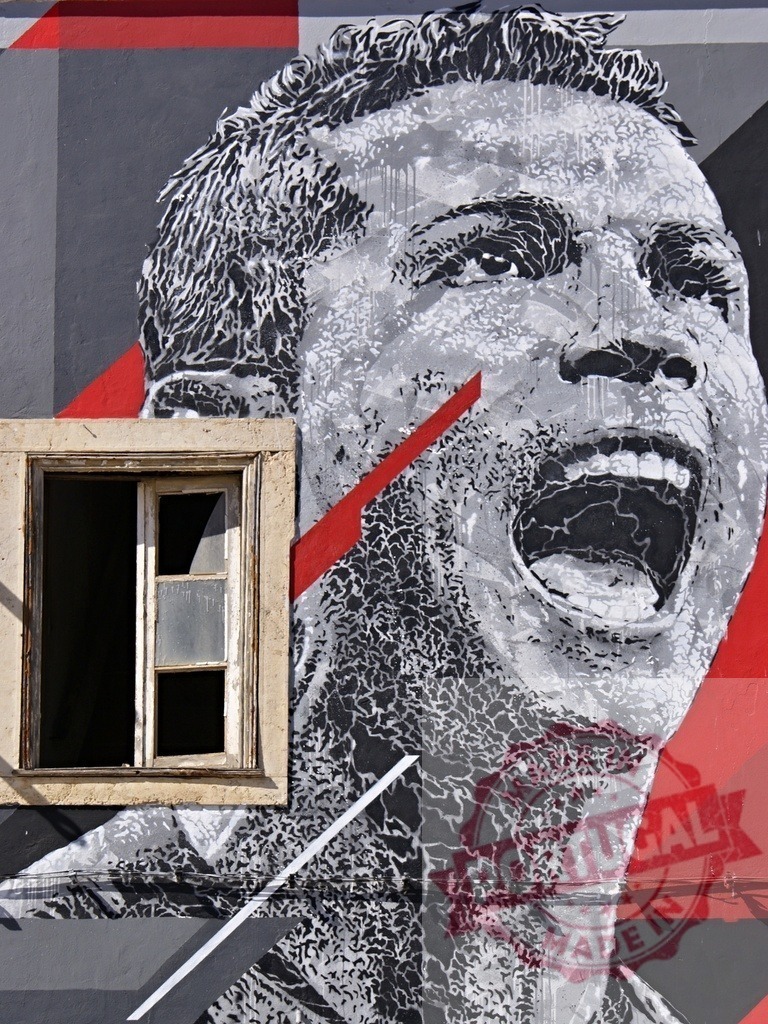 Cristiano Ronaldo street art mural in Lisbon Portugal | Portrait of shouting CR7 painted on an urban wall next to a window - Realized with Pictrs.com