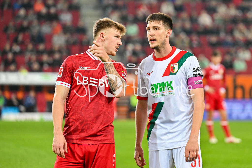 FC Augsburg - VfB Stuttgart | AUGSBURG, GERMANY - 22. MAERZ: im Gespräch Finn JELTSCH (VfB Stuttgart 29) und Keven SCHLOTTERBECK (FC Augsburg 31) während dem Bundesligamatch zwischen dem FC Augsburg und dem VfB Stuttgart am 27. Spieltag in der WWK Arena / DFL REGULATIONS PROHIBIT ANY USE OF PHOTOGRAPHS AS IMAGE SEQUENCES AND/OR QUASI-VIDEO
