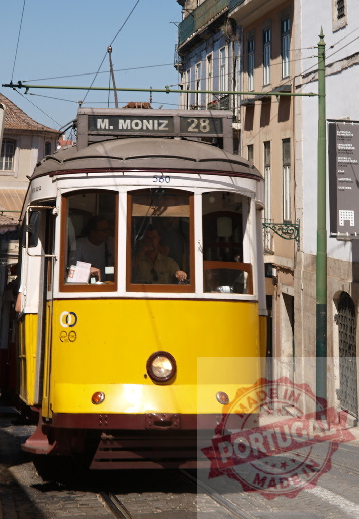 Yellow Tram Number 28 Climbing up a Narrow Street in Lisbon | Remodeled Lisbon tram number 28 climbing up a narrow street, with driver and passengers inside, in Lisbon, Portugal - Realized with Pictrs.com