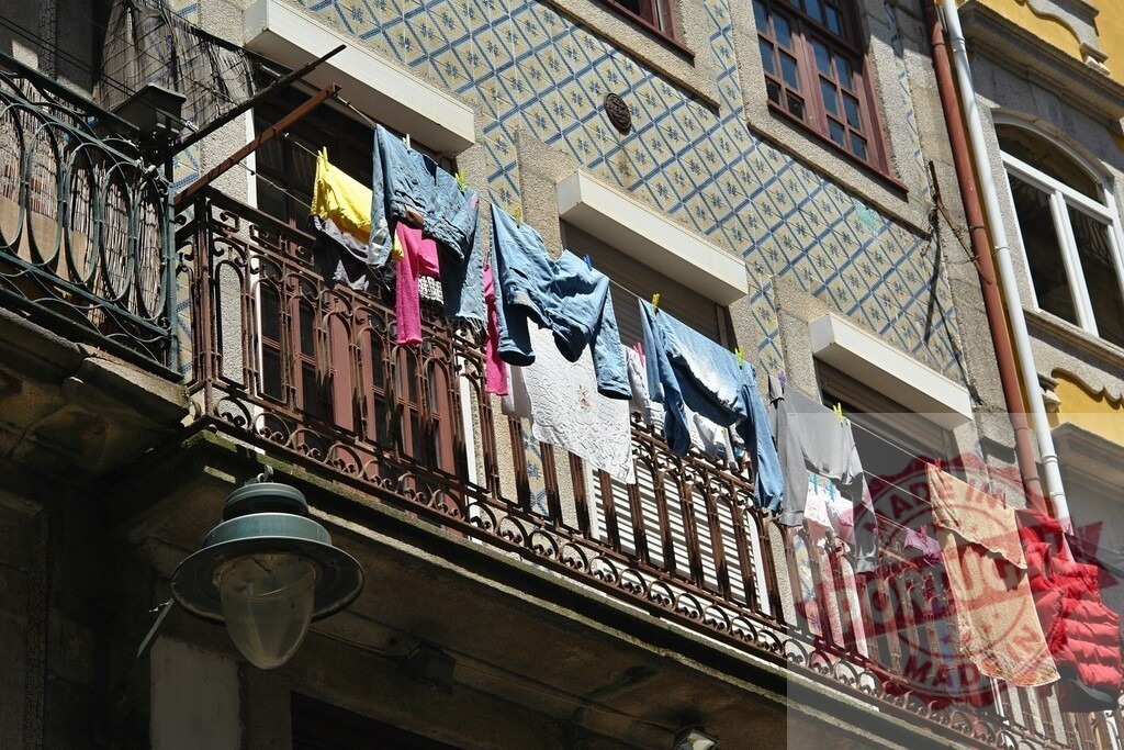 Laundry hanging on a balcony in Porto, Portugal | Laundry hanging on clothesline from a traditional Porto balcony with azulejos facade - Realized with Pictrs.com