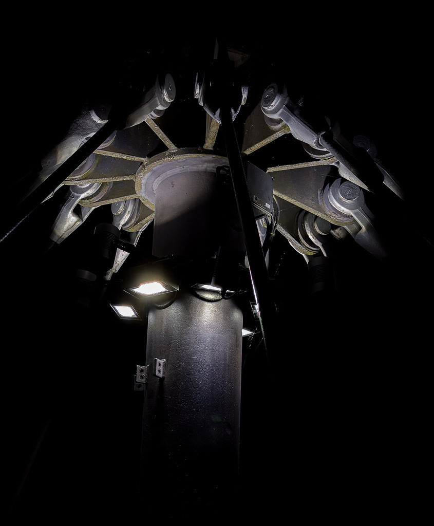 Wandbild Cyber-Industrial - Abstrakte Schwarz-Weiß-Geometrie | Dieses monumentale Schwarz-Weiß-Wandbild fasziniert durch eine fast surreale, futuristische Ästhetik. Die meisterhafte High-Contrast-Aufnahme zeigt eine komplexe Industriestruktur von unten, die sich dem Betrachter erst auf den zweiten Blick erschließt. Das absolut symmetrische, strahlenförmige Design erinnert an Science-Fiction-Konstrukte, ein kybernetisches Auge oder ein außerirdisches Raumschiff. Fotograf Robert Steinke inszeniert das hocheffektive Zusammenspiel aus gleißendem Licht, tiefschwarzen Schatten und rauer, metallischer Haptik in gestochen scharfer Premium-Qualität. Ein kompromissloses Kunst-Statement für moderne Lofts, minimalistische Wohnräume oder progressive Büros. Perfekt geeignet als großformatiger Premium-Kunstdruck auf Alu-Dibond oder hinter glänzendem Acrylglas für eine atemberaubende Tiefenwirkung. - Realisiert mit Pictrs.com
