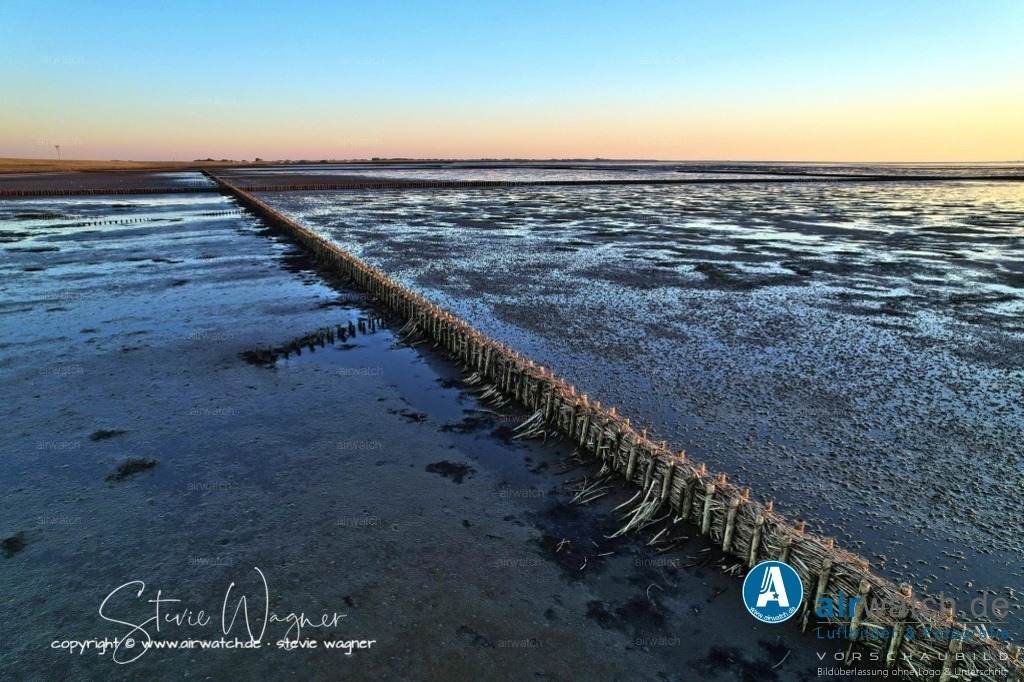 Nordsee, Nordfriesland, Beltringharderkoog, Luettmoorsee, Holmer Siel, Landgewinnung | Landgewinnung & Küstenschutz in Nordfriesland - Um die Aufschlickung zu beschleunigen, werden sogenannte Lahnungsfelder angelegt. Diese sind doppelte Reihen von Holzpfählen, die in den Wattboden gerammt werden. Zwischen die Pfähle werden Zweige und Reisigbündel gepackt. Diese Lahnungsfelder teilen das Watt in rechteckige Felder, in denen das auflaufende Wasser schneller zur Ruhe kommt. Dadurch können die Schwebeteilchen, die das Meer mitbringt, besser absetzen und neue Landflächen entstehen.