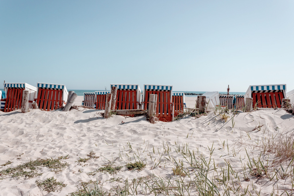 Wandbild: Strandkörbe am Meer | Dieses Wandbild im Querformat zeigt zahlreiche Strandkörbe hinter einer kleinen Sanddüne. Es bringt den Urlaub zu Ihnen nach Hause. Im Vordergrund bietet der Sandstrand einen natürlichen Sandton und der Himmel leuchtet in einem pastellartigen blau. Durch den hellen Farbton passt dieses Wandbild zu fast jedem Einrichtungsstil. Dieses Wandbild ist auf Leinwand, Aluminium-Platte, Acrylglas oder als Holzdruck erhältlich. Die Wandbilder werden individuell für Sie in vielen Abmessungen produziert. Daher passen die Ostseekult Wandbilder immer perfekt an Ihre Wände. - Realisiert mit Pictrs.com