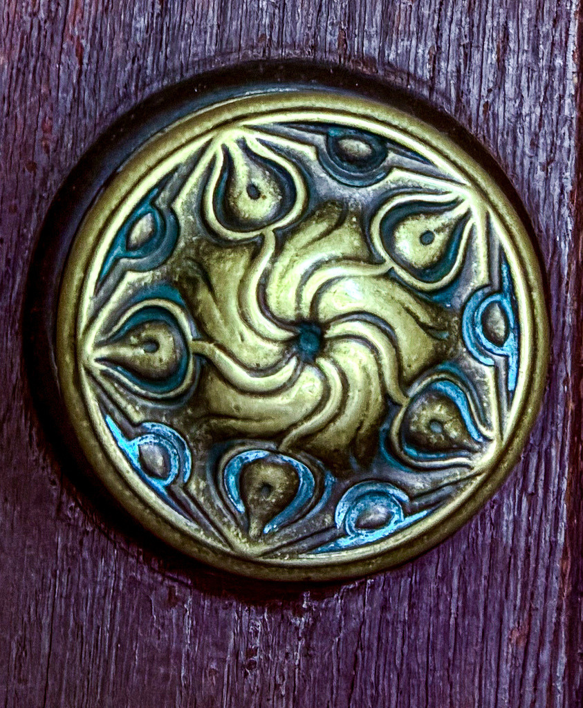 The Golden Vortex – Antike Ornament-Fotokunst aus Lörrach | Ein faszinierendes Zeugnis historischer Handwerkskunst, festgehalten in moderner High-End-Fotografie. Dieses exklusive Wandbild zeigt die detailreiche Nahaufnahme eines kunstvoll verzierten, antiken Türknaufs aus der Region Lörrach. Das hypnotische, wirbelförmige Relief aus patiniertem Metall bricht das Licht auf meisterhafte Weise und bildet einen edlen Kontrast zur tiefen, dunklen Holzstruktur im Hintergrund. Ein zeitloses Kunstwerk voller Charakter, Mystik und urbaner Geschichte.Material-Empfehlung: Für dieses metallische Meisterwerk mit seinen feinen Strukturen und der blau-goldenen Patina empfehle ich das Motiv hinter glänzendem Acrylglas. Es verleiht den metallischen Reflexen eine spektakuläre Dreidimensionalität und bringt die Farben magisch zum Leuchten.Bringen Sie ein Stück historische Eleganz und exklusive Fotokunst in Ihre Räume. Sichern Sie sich dieses ausdrucksstarke Kunstwerk jetzt für Ihre Galerie.[Archiv-Nr. #0109] - Realisiert mit Pictrs.com