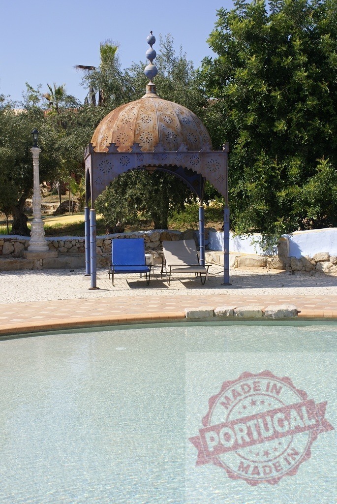 Swimming pool with ornate metal gazebo and lounge chairs | Gazebo and lounge chairs next to a clear swimming pool offering relaxation - Realized with Pictrs.com