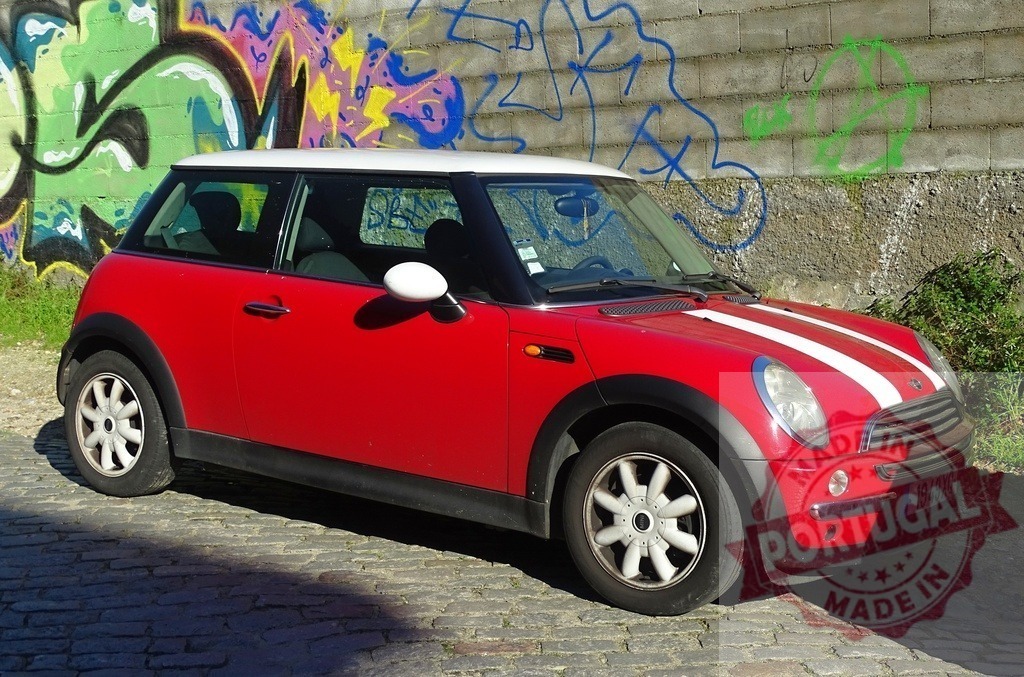 Mini Cooper car parked on cobblestone street with graffiti wall | Red Mini Cooper car parked on a cobblestone street, graffiti painted on a wall in the background - Realisiert mit Pictrs.com