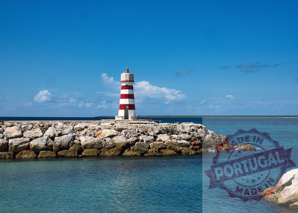 Red and white striped lighthouse on rocky coast | Tall lighthouse standing on a rock breakwater with clear blue ocean and sky - Realized with Pictrs.com