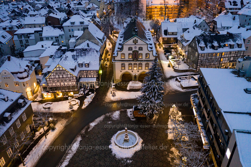 Drohnenaufnahme zeigt verschneites Rathaus und Brunnen von Brilon zur Weihnachtszeit | Luftbild zeigt den Briloner Marktplatz an einem Winterabend. Stimmungsvolles winterliches Bild des beleuchteten Stadtzentrums im Schnee.