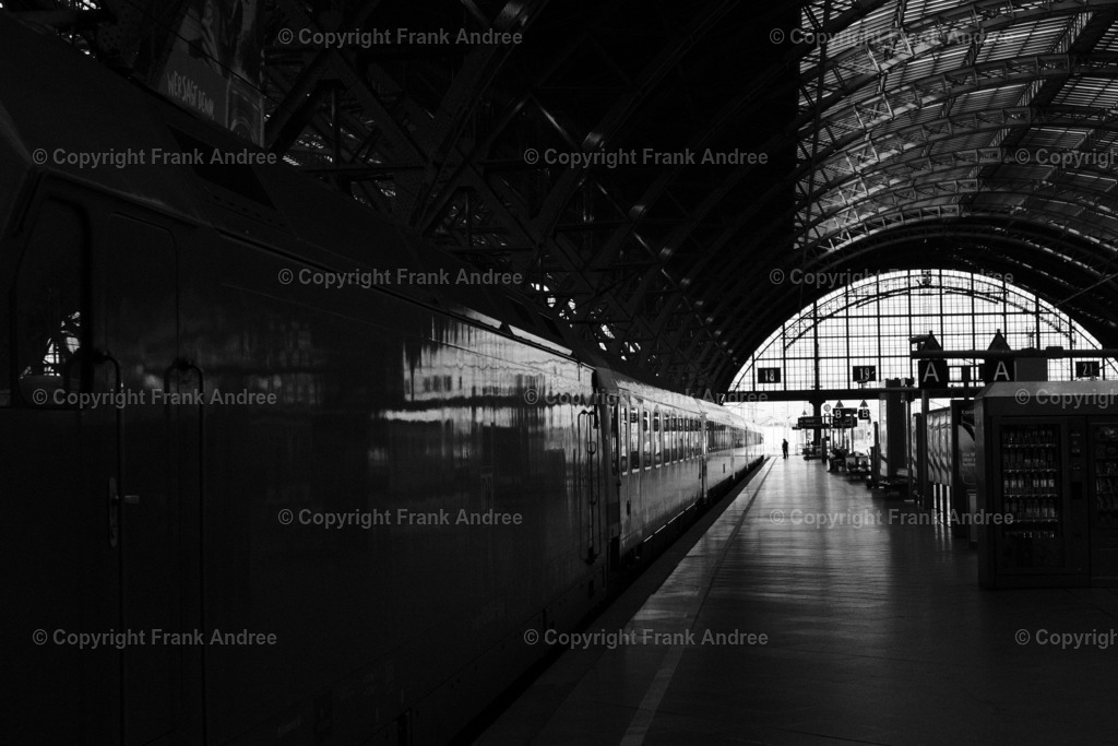 Leipzig Hauptbahnhof | Auf einem Bahnsteig des Leipziger Hauptbahnhofessteht ein Zug . Am Ende des Bahnsteigs unterhalten sich zwei Menschen, Schwarz weiß Straßenfotografie aus Deutschland - Realisiert mit Pictrs.com