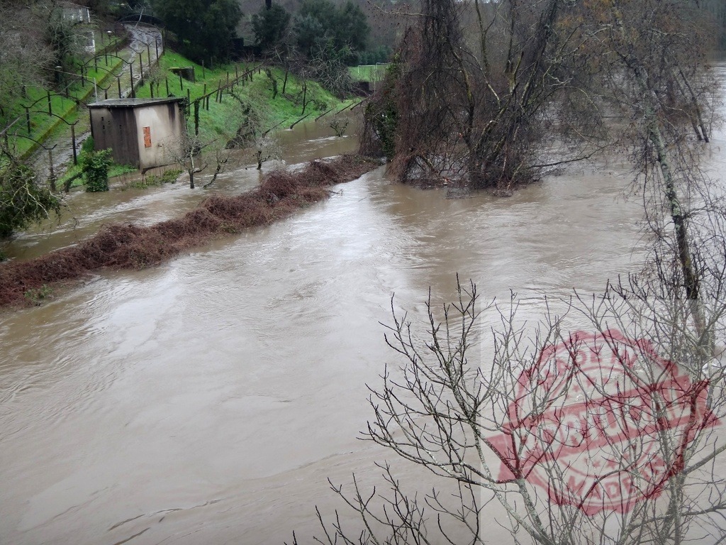 Muddy river overflowing banks during winter flood event. Portugal floods 02.26 - Paco de Sousa, Penafiel | Muddy river overflowing its banks, partially submerging buildings and trees in a natural disaster - Realisiert mit Pictrs.com