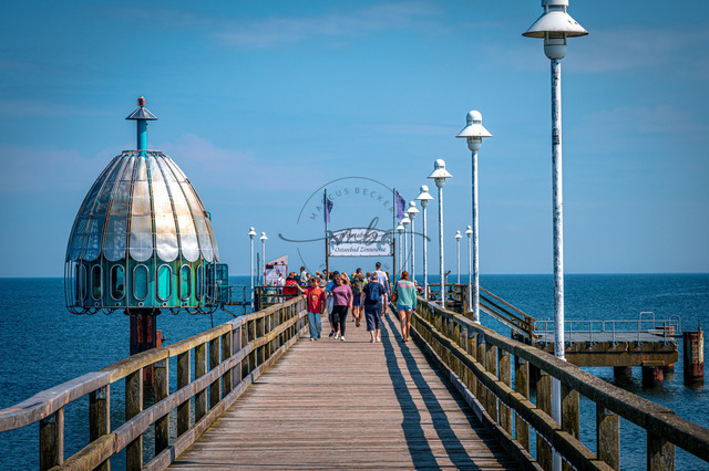 2026-08-05_11-07-19_140 | Menschen spazieren auf der Seebrücke unter klarblauem Himmel, umgeben von Wasser und Licht, Zinnowitz, Usedom, Mecklenburg-Vorpommern, Deutschland - Realisiert mit Pictrs.com