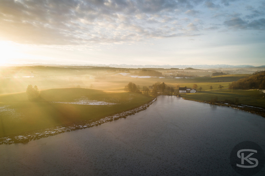 Allgäu-See-Landschaft zum Sonnenaufgang aus der Luft mit Mischwald im Herbst | Atemberaubende Allgäu-See-Landschaft aus der Luft mit farbenprächtigem Mischwald im Herbst – Sonnenaufgang mit dramatischem Himmel in idyllische Natur, leuchtende Herbstfarben für beeindruckende Drohnenaufnahme - Realisiert mit Pictrs.com