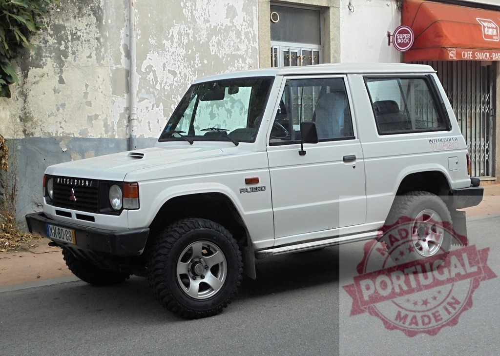 White Mitsubishi Pajero parked on a residential street in Portugal | White Mitsubishi Pajero SUV with off-road tires parked on a street in Portugal - Realisiert mit Pictrs.com