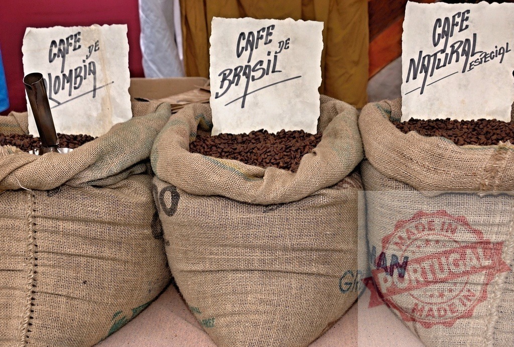 Coffee beans from Colombia, Brasil, and natural variety in sacks | Burlap bags holding roasted coffee beans from different origins, ready for sale at a market - Realized with Pictrs.com