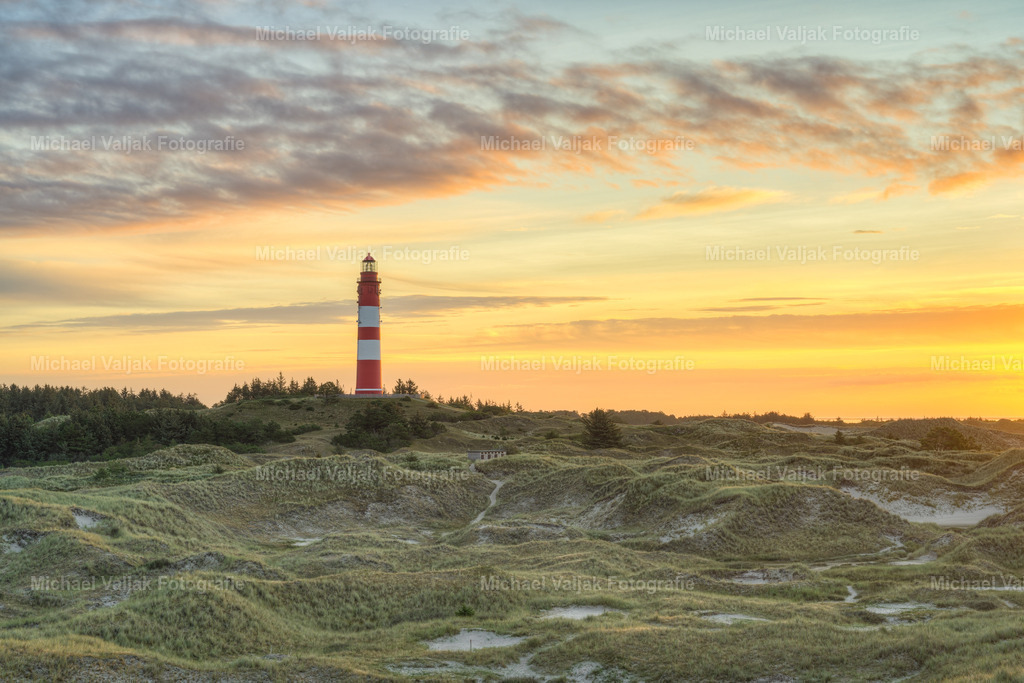 Leuchtturm auf Amrum bei Sonnenaufgang | Amrum, eine der nordfriesischen Inseln in Deutschland, ist bekannt für ihre malerischen Landschaften, die besonders bei Sonnenaufgang atemberaubend sind. Der Blick über die sanften Dünen hinweg zum Leuchtturm, der stolz über das Meer wacht, ist ein beliebtes Motiv für Fotografen und Naturbegeisterte. Dieses idyllische Szenario spiegelt die ruhige Schönheit der Insel wider und lädt Besucher dazu ein, die Stille des Morgens zu genießen, während die ersten Sonnenstrahlen den Himmel erleuchten. - Realisiert mit Pictrs.com