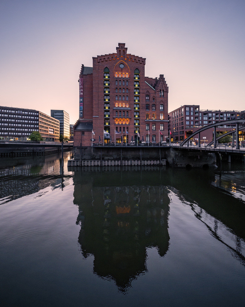 Speichergebäude mit Spiegelung in der HafenCity | Frontale Ansicht eines historischen Speichergebäudes mit markanter Spiegelung im Wasser zwischen Speicherstadt und HafenCity. - Realisiert mit Pictrs.com