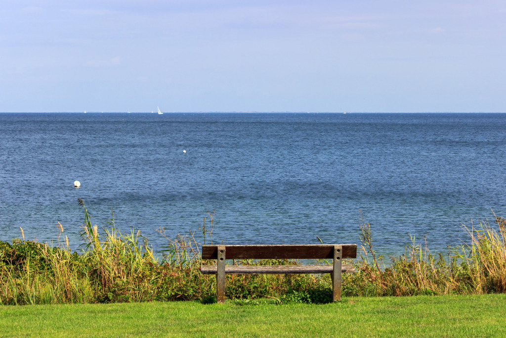 Wandbild: Strand in Norgaardholz | Dieses Wandbild im Querformat zeigt eine Bank zum verweilen am Strand in Norgaardholz. Direkt dahinter befindet sich die offene Ostsee. - Realisiert mit Pictrs.com