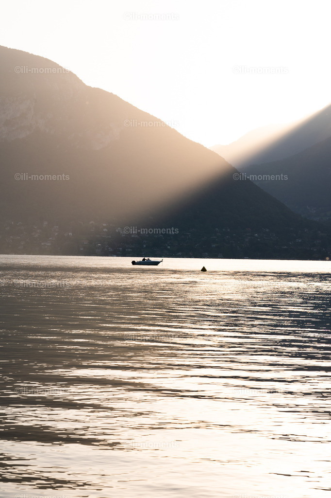Der erste Sonnenstrahl | „Der erste Sonnenstrahl“ ist ein atmosphärisches Naturfoto, das die Magie des Morgens in den Bergen auf einzigartige Weise einfängt. Hinter dem felsigen Bergmassiv bricht der erste Sonnenstrahl des Tages hervor und taucht die Szenerie in ein warmes, goldenes Licht. Im Vordergrund liegt ein ruhiger, spiegelglatter See, auf dem ein kleines Anglerboot sanft ruht – ein Symbol für Stille, Konzentration und das Innehalten vor einem neuen Tag.Die kraftvolle Kombination aus Licht, Landschaft und minimalistischem Bildaufbau macht dieses Foto zu einem stimmungsvollen Kunstwerk, das besonders in Wohnräumen, Büros, Hotels, Wellnessbereichen oder Bergchalets seine volle Wirkung entfaltet. - Realisiert mit Pictrs.com