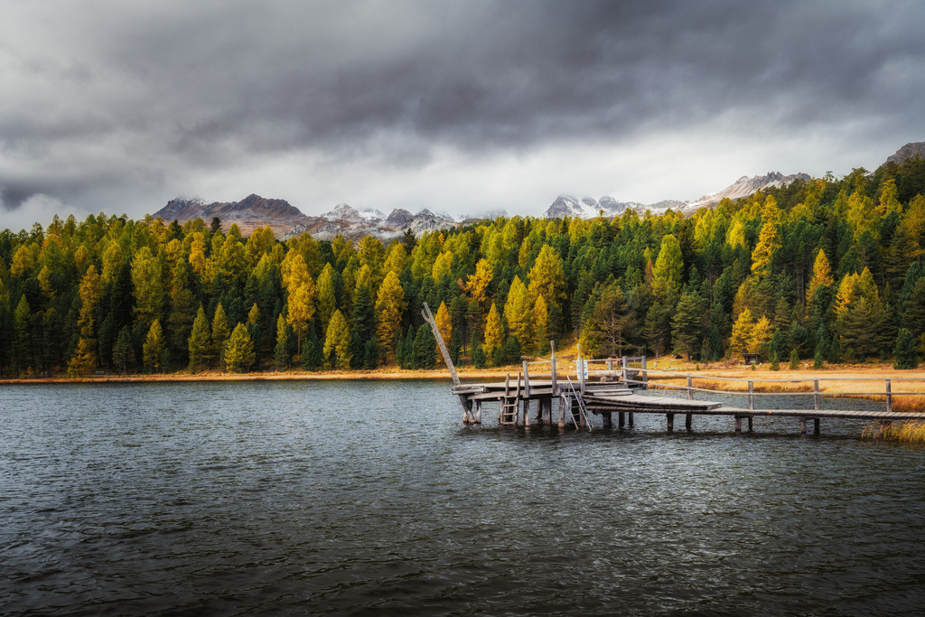 Stazersee in Celerina | Aufkommende dunkle Wolken werden durch Sonnenstrahlen durchbrochen und beleuchten den See. - Realisiert mit Pictrs.com