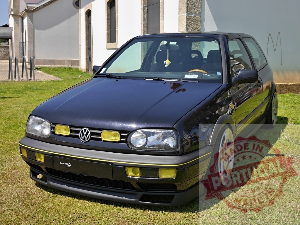 Volkswagen Golf Mk3 custom tuned hatchback on grass | Volkswagen Golf Mk3 displaying custom tuning modifications and yellow fog lights on a sunny day - Realized with Pictrs.com