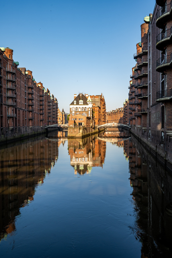 Speicherstadt am ruhigen Fleet | Stimmungsvolle Ansicht der Speicherstadt mit ruhigem Fleet, sanften Spiegelungen und klassischer Hamburger Architektur. - Realisiert mit Pictrs.com