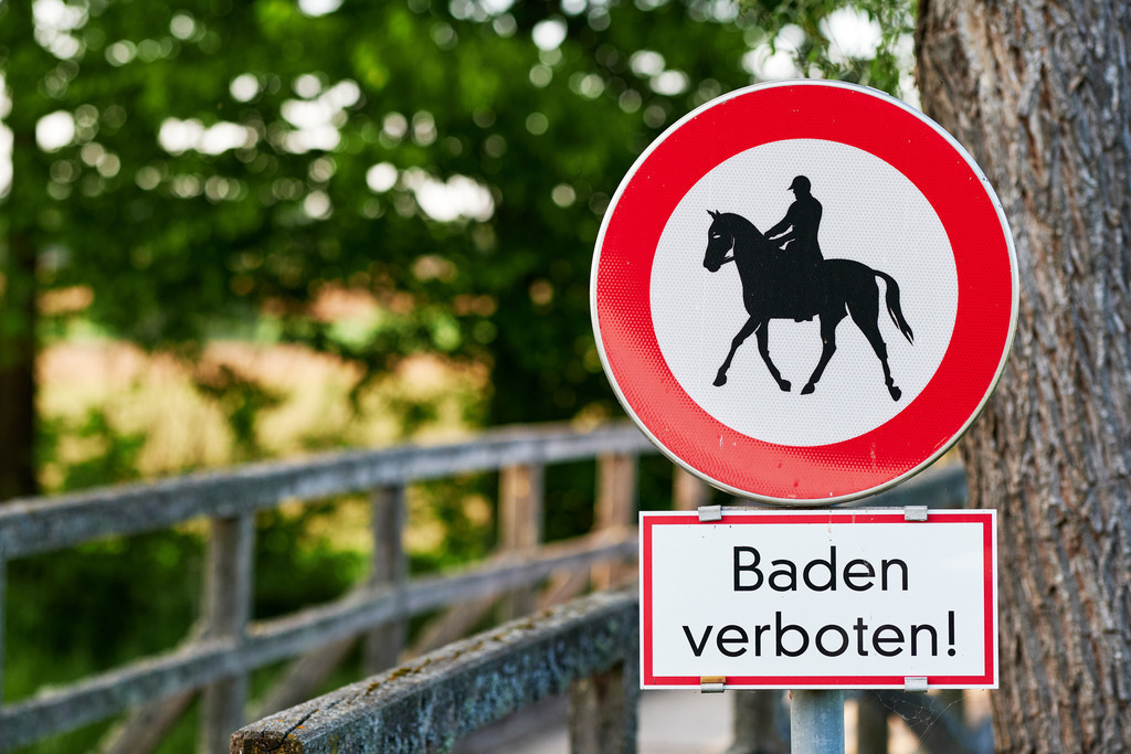 Bade und Reiten verboten Schild | Burgenland, Austria - May 08, 2020: Badeverbot und Reiten verboten Schild vor einer Holzbrücke. - Realisiert mit Pictrs.com