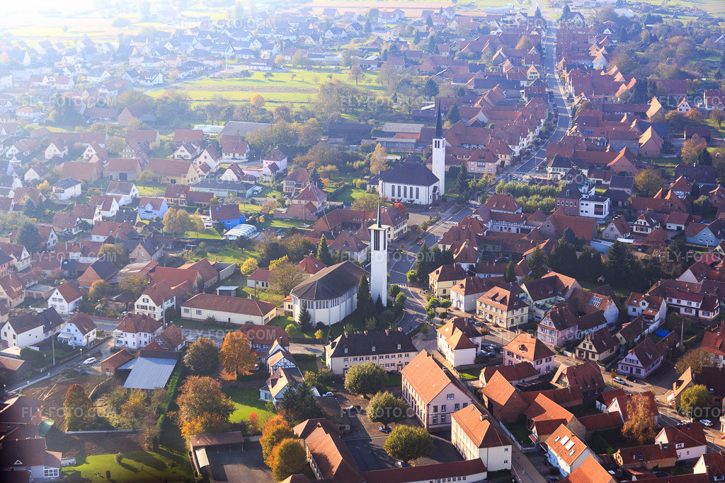 Aerial view: Two churches in the village center in Hatten in the state Bas-Rhin, France. – Photo: IMG_075642.jpg taken on 11/01/2014 by Werner Riehm/FLY-FOTO.com – Resolution of the original: 5251 x 3501 px