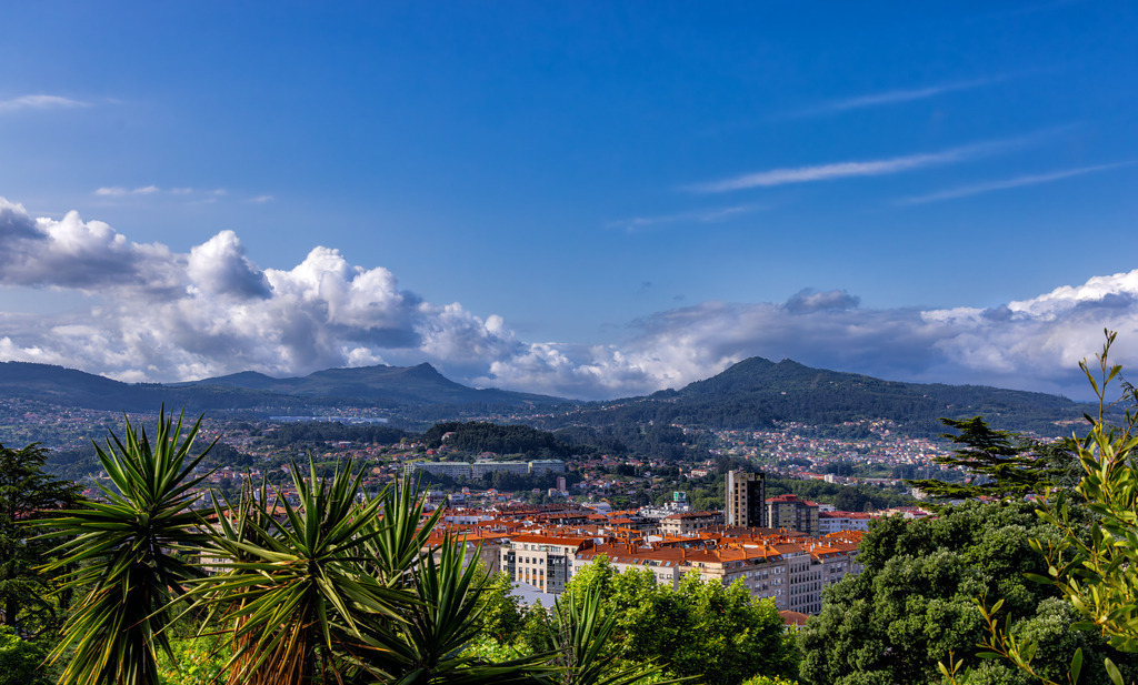 Panorama von Vigo--Galicien--Fernblick über die Hügelkette | Die Aufnahme zeigt eine Panoramaansicht der Stadt Vigo in Galicien, Spanien, aufgenommen vom Monte do Castro. Vigo ist eine Hafen- und Industriestadt, die sich an den Hängen des Monte del Castro erstreckt und einen Naturhafen überblickt. Der Monte do Castro ist ein Stadtpark und gilt als der Ursprungsort der Stadt Vigo, wo Überreste von iberischen Burgen gefunden wurden.  - Realisiert mit Pictrs.com