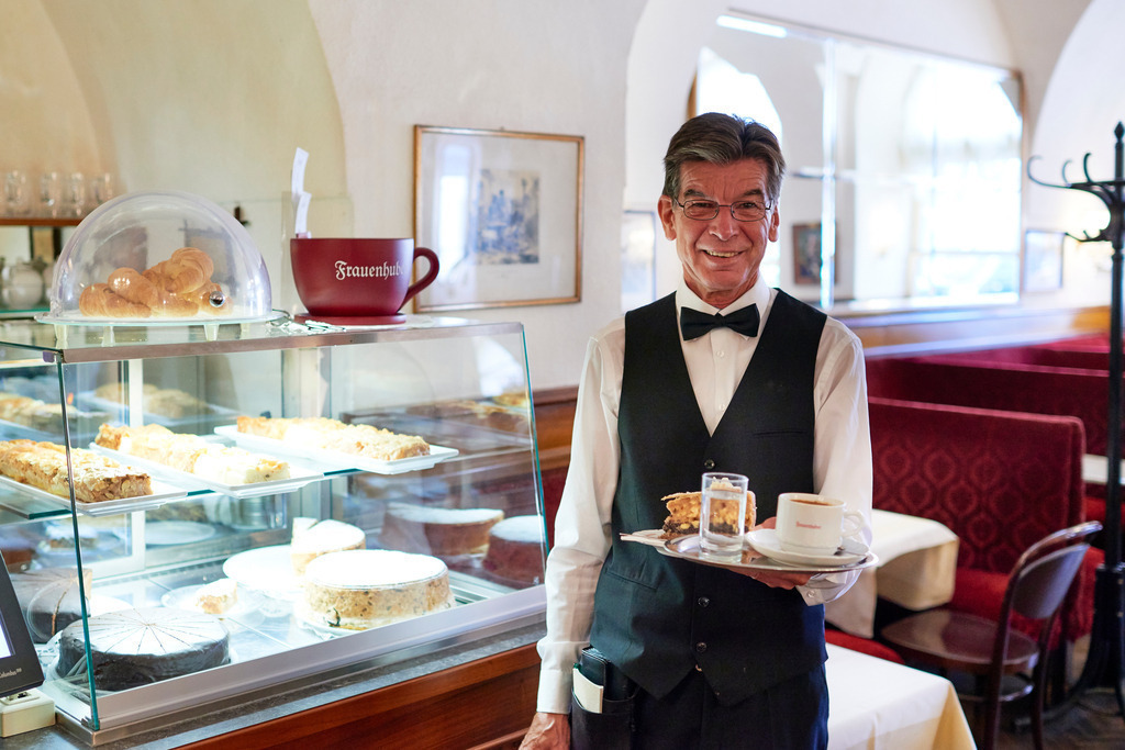 Cafe Frauenhuber | Wien, Austria - August 23, 2017: Cafe Frauenhuber, Herr Hannes serviert eine Haustorte mit Schlagsahne und Melange. - Realisiert mit Pictrs.com