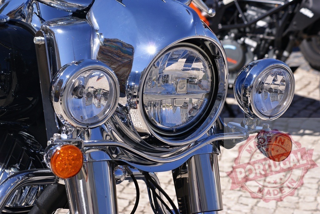 Classic motorcycle chrome headlight with orange turn signal | Close-up of motorcycle chrome, reflecting a sunny day with polished metal and lights - Realized with Pictrs.com