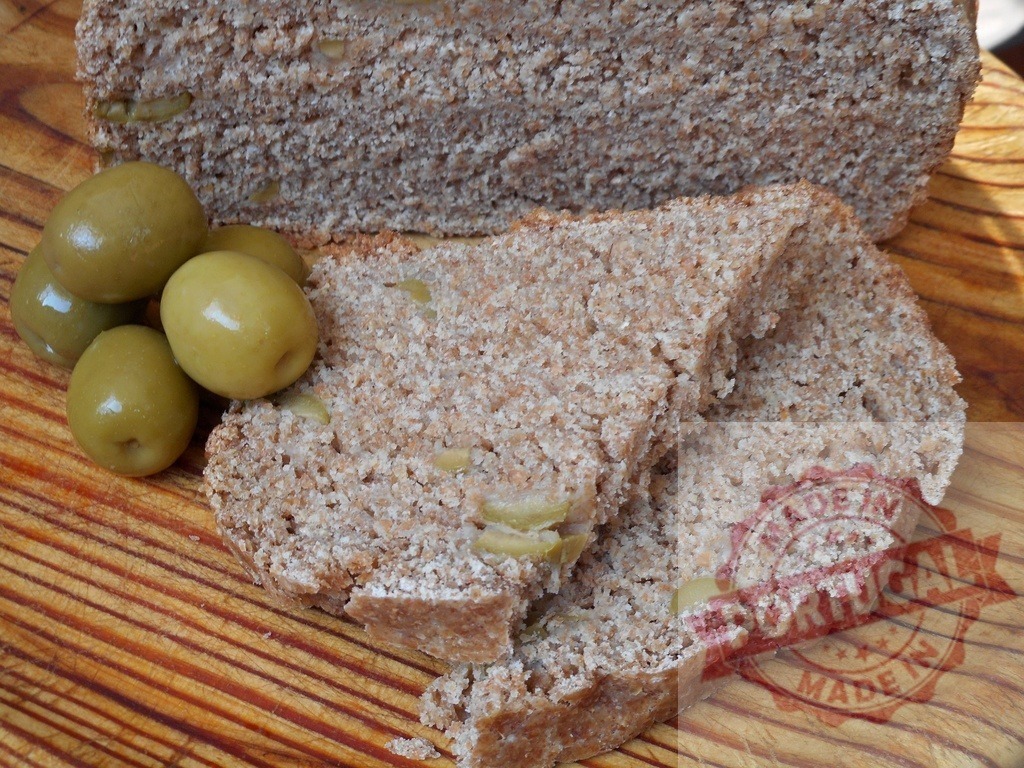 Whole wheat olive bread loaf with sliced portions | Whole wheat bread mixed with green olives, sliced on a rustic wooden board - Realized with Pictrs.com