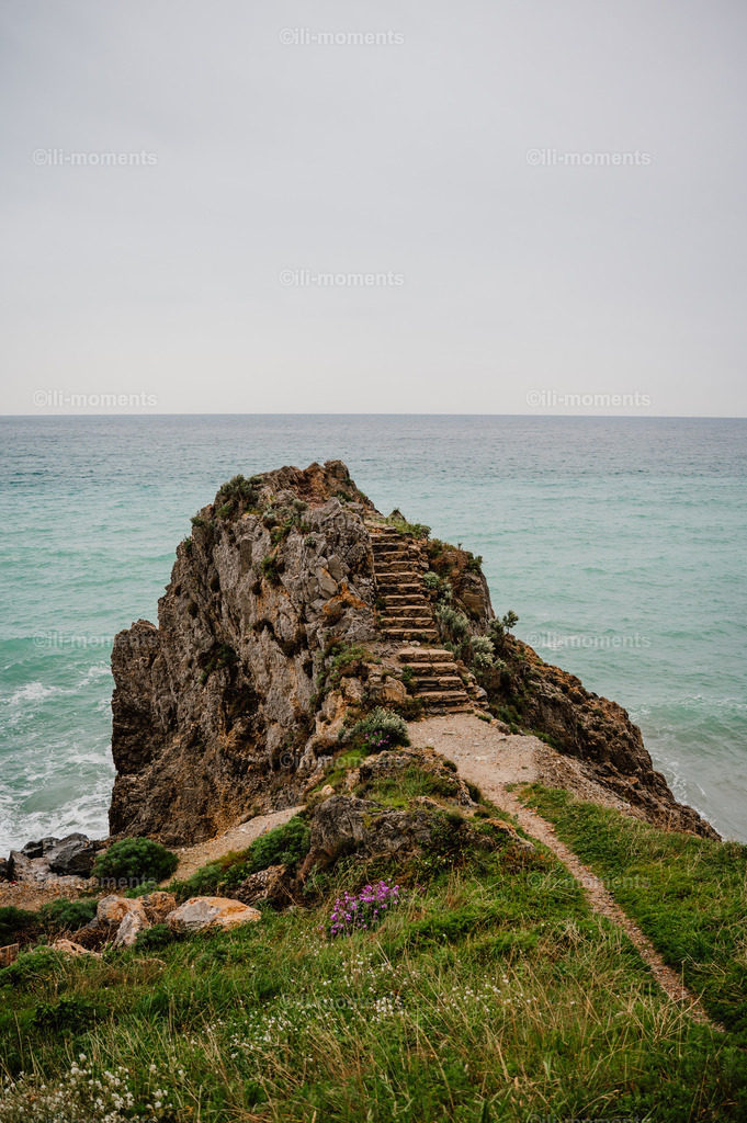 Treppe zur Aussicht | Eine Treppe führt über felsiges Gelände zum atemberaubenden Ausblick aufs Mittelmeer – ein faszinierendes Fotokunstwerk voller Freiheit und Naturkraft. Perfekt als Kunstdruck für inspirierende und naturnahe Räume. - Realisiert mit Pictrs.com
