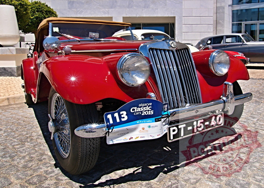 Classic red convertible displayed at a car show event | Vintage Red Convertible Showcased at Algarve Classic Cars - Realized with Pictrs.com