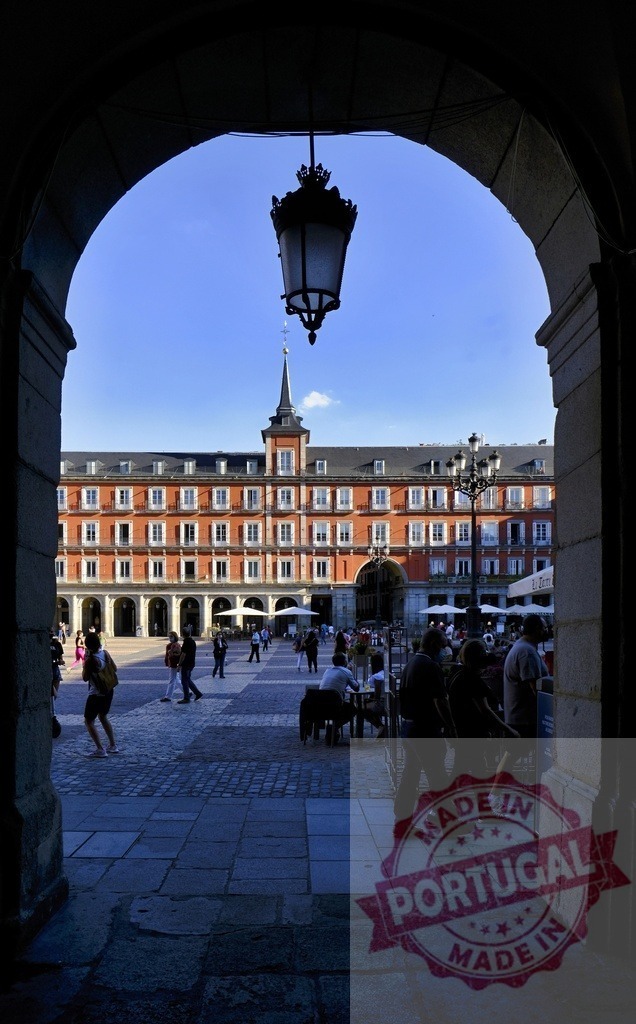 Plaza Mayor Madrid archway overlooking historic square | Plaza Mayor's iconic architecture frames a bustling square with people enjoying outdoor cafes - Realized with Pictrs.com