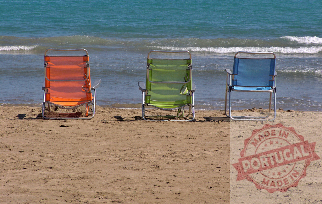 Three colorful beach chairs standing on sand by sea. Provincia de Castellon | Three colorful chairs awaiting guests on a sandy beach next to the ocean - Realized with Pictrs.com