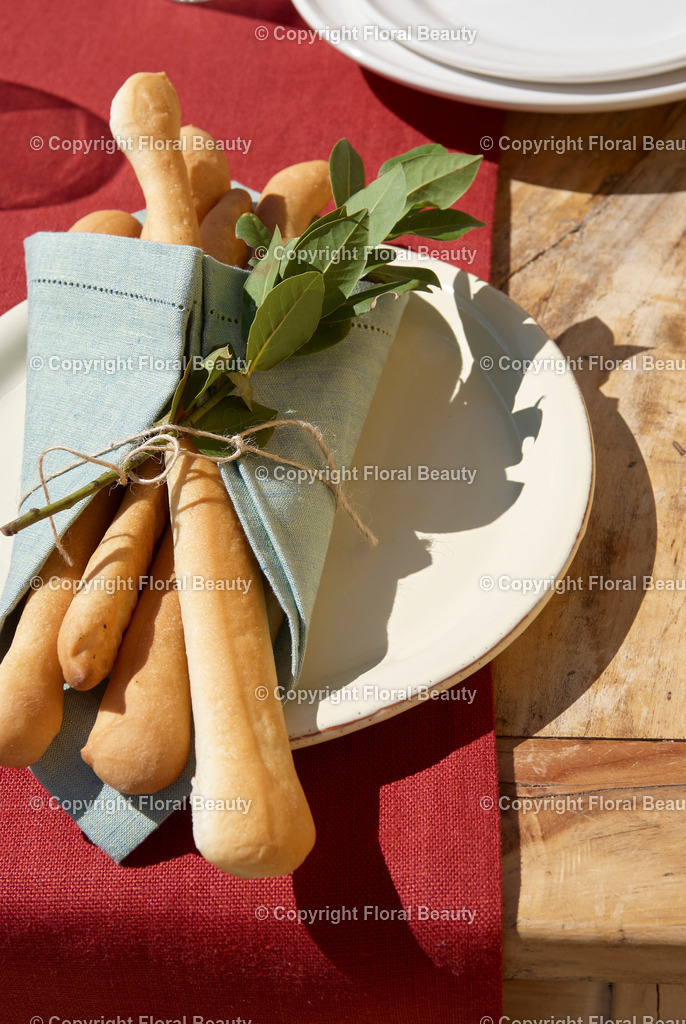 Weingut in Italien | italienisches Stangenbrot hübsch dekoriert mit Lorbeerzweig auf Teller in der Sonne - Realisiert mit Pictrs.com