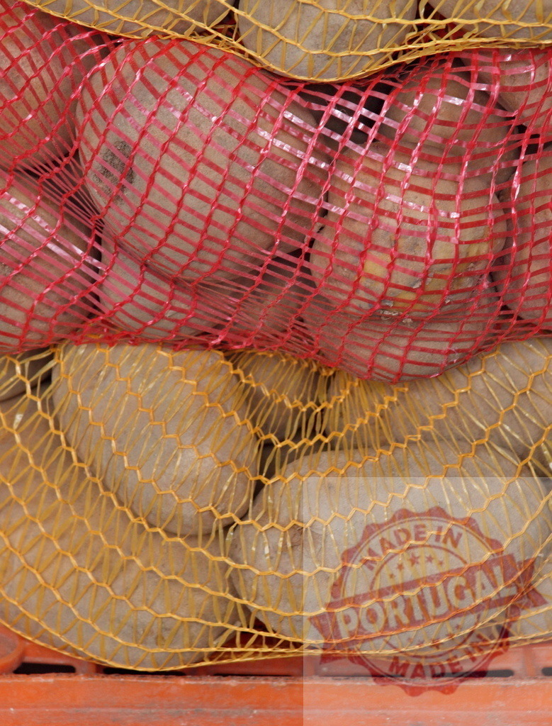 Potatoes in red and yellow mesh sacks | Potatoes fresh from harvest packaged in mesh sacks for market - Realized with Pictrs.com