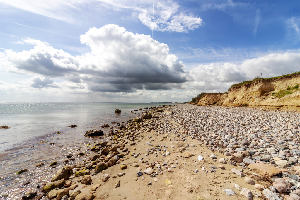 XXL Wandbild: Steilküste an der Ostsee im Frühling | Dieses XXL Wandbild im Querformat zeigt einen Naturstrand mit schöner Steilküste im Frühling. Am blauen Himmel sind malerische Wolken zu sehen. - Realisiert mit Pictrs.com