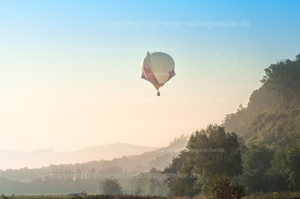 Atmosphärische Ansicht eines Heißluftballons im Frühnebel über Naturlandschaft | Ein Heißluftballon startet seinen Flug. Es ist früher Morgen, der Nebel liegt über der Natur. Der Ballon hat eine ungewöhnliche Form. Warsteiner Internationale Montgolfiade.