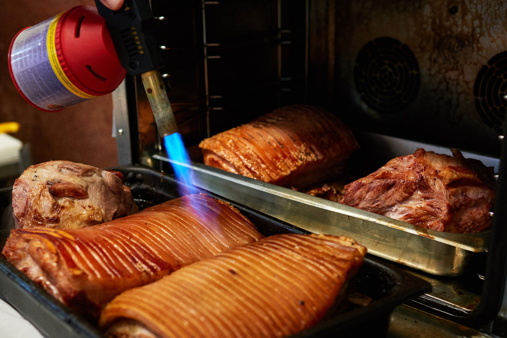 Fleischerei Dormayer | Langenzersdorf, Austria - February 12, 2019: Fleischerei Dormayer; mit einem Bunsenbrenner wird die Kruste beim Schweinsbraten gemacht. - Realisiert mit Pictrs.com