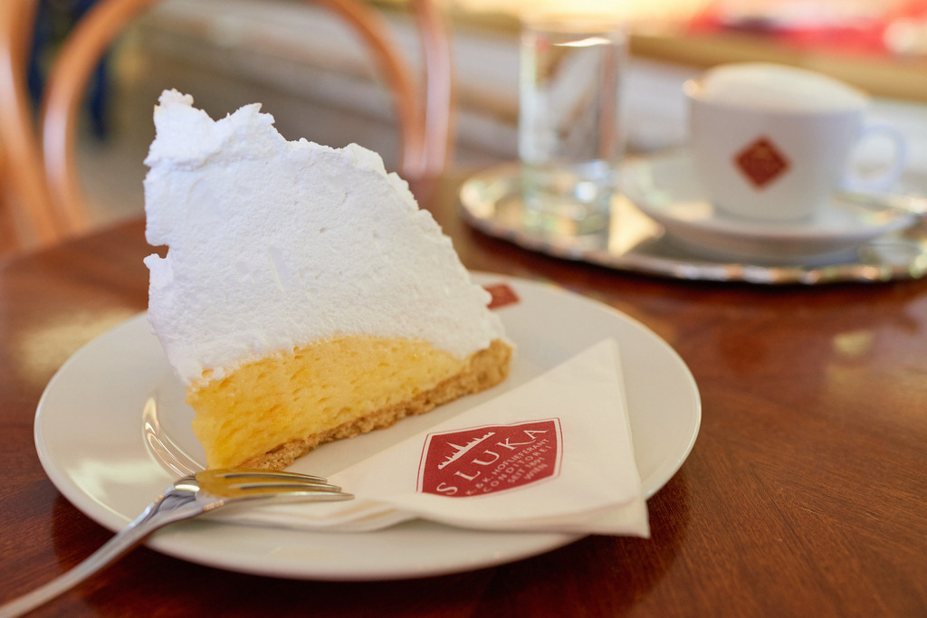 Cafe Sluka - Zitronenschaumtorte | Wien, Austria - March 28, 2018: Conditorei Sluka Rathausplatz; eine Zitronenschaumtorte und eine Tasse Melange stehen auf dem Tisch. - Realisiert mit Pictrs.com