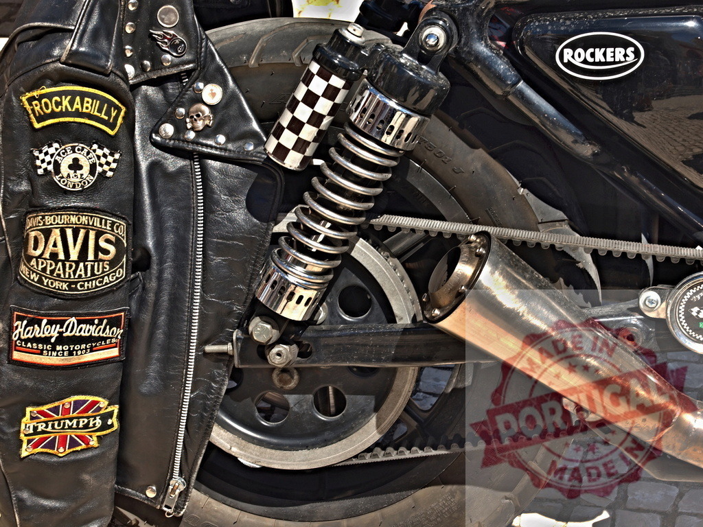 Black leather motorcycle jacket with Rockabilly and Harley-Davidson patches | Black leather jacket displaying vintage patches leaning against a custom motorcycle - Realisiert mit Pictrs.com