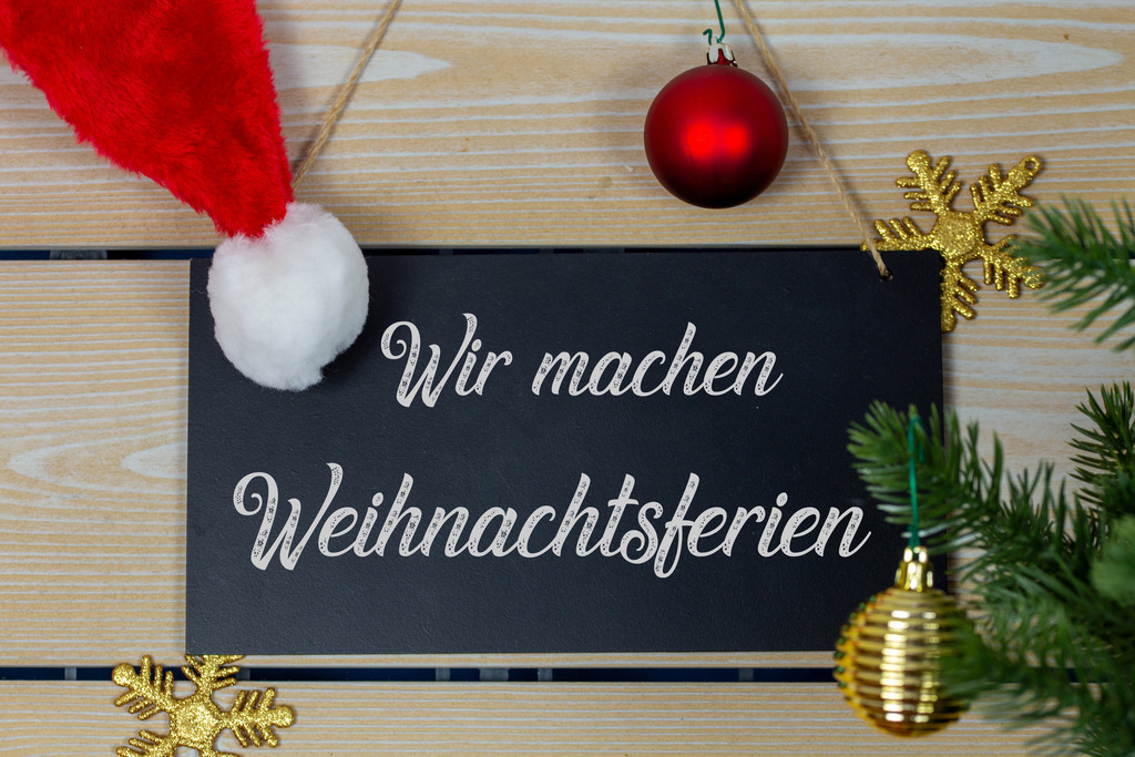 WIR MACHEN WEIHNACHTSFERIEN | Weihnachtsgrüße: Schild mit dem Schriftzug WIR MACHEN WEIHNACHTSFERIEN mit weihnachtlicher Dekoration - Realisiert mit Pictrs.com