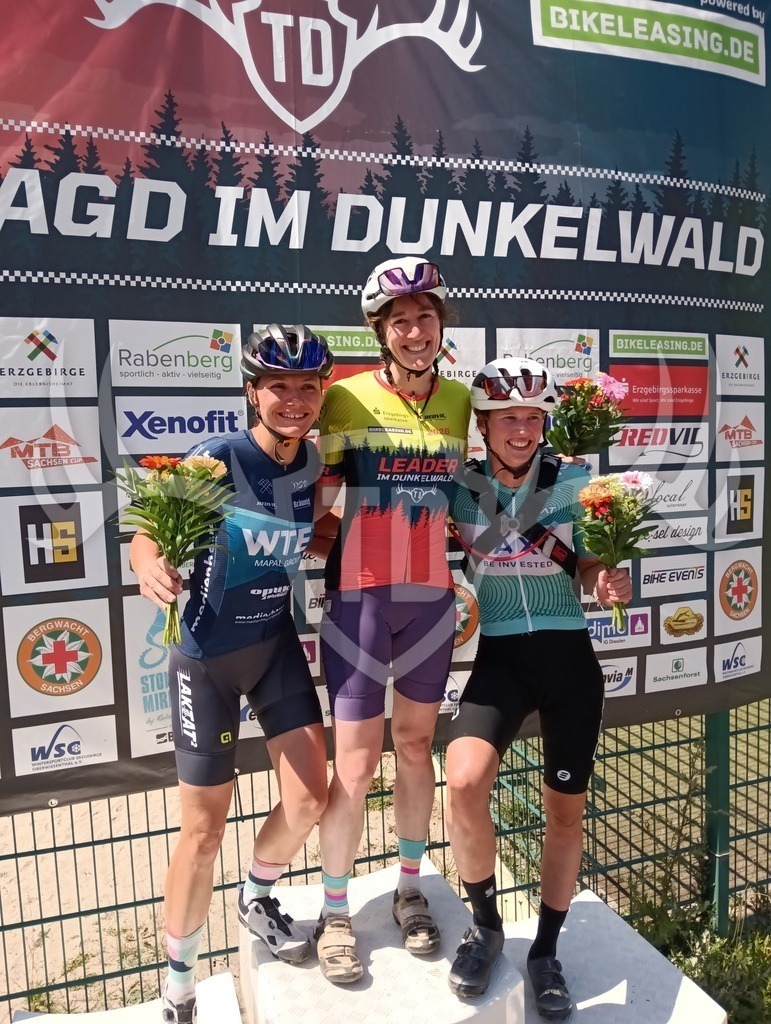 Blumenzeremonie | Täglich werden die drei schnellsten Frauen und Männer direkt nach der Zieleinfahrt mit Blumen geehrt. Hier die drei schnellsten Frauen der Kurzstrecke vom Dunkelwald Marathon am Freitag. - Realisiert mit Pictrs.com