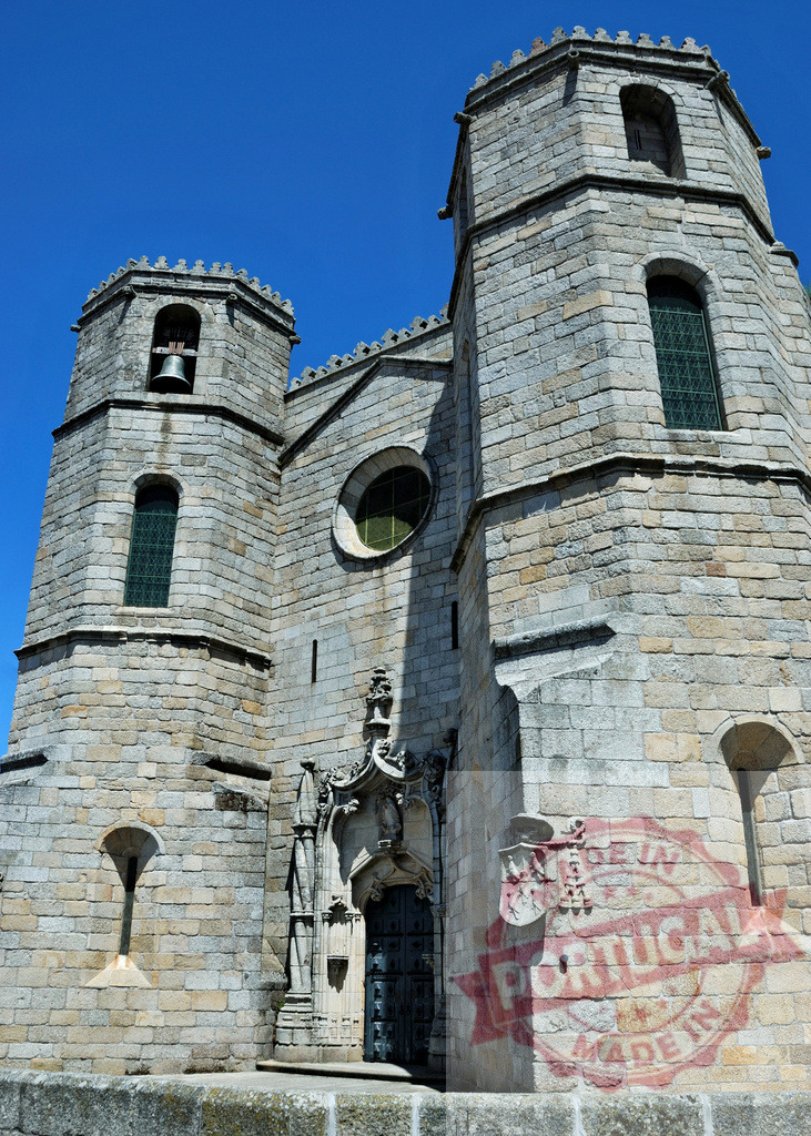 Bragança cathedral church towers against blue sky. Region Norte - Portugal | Old stone cathedral featuring bell towers and ornate entrance under clear sky - Realized with Pictrs.com